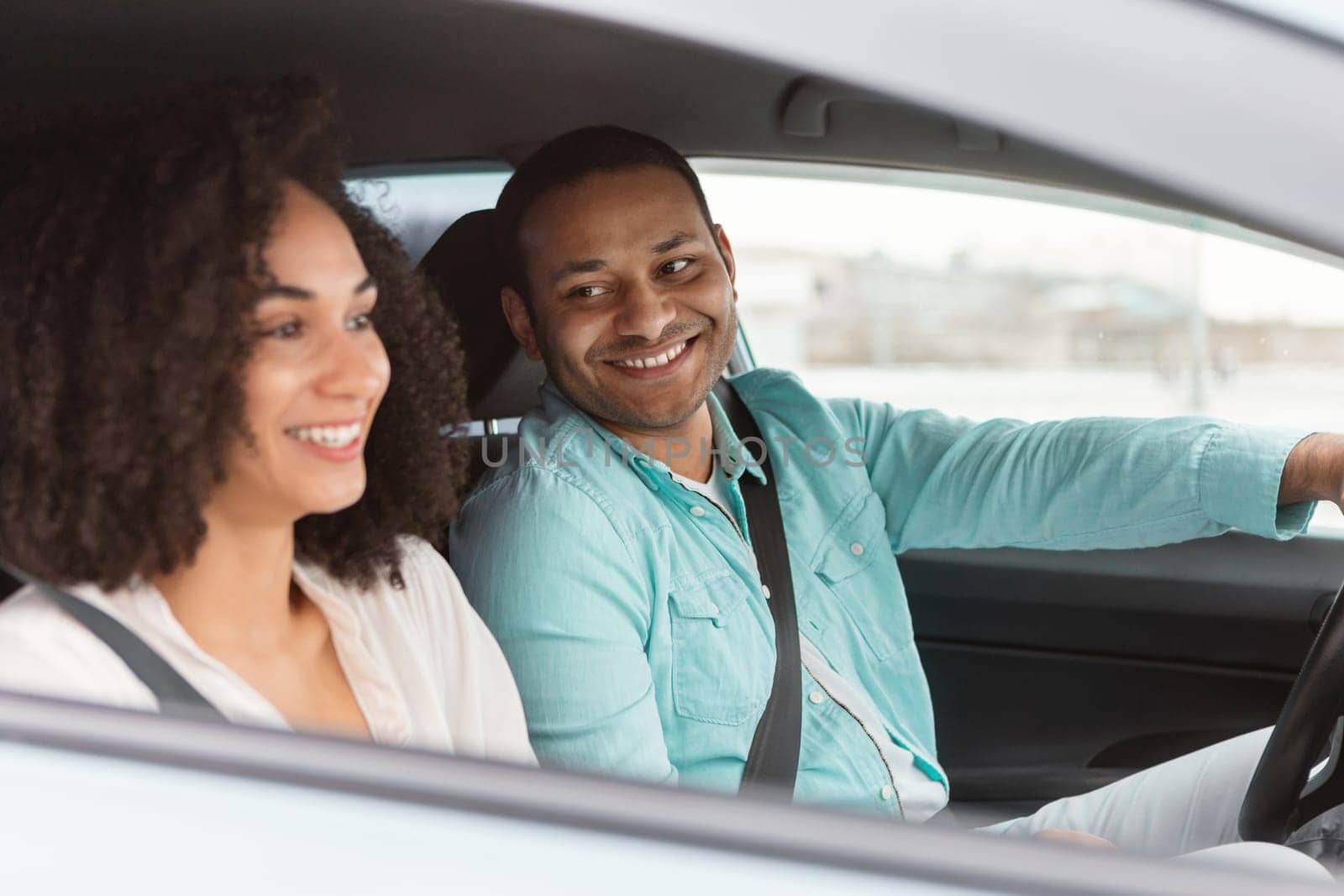 Owning A Car. Happy Middle Eastern Couple Driving Enjoying Journey By Vehicle, Man Driver Smiling To His Wife Traveling By New Automobile Sitting Inside. Rent And Leasing Offer. Selective Focus