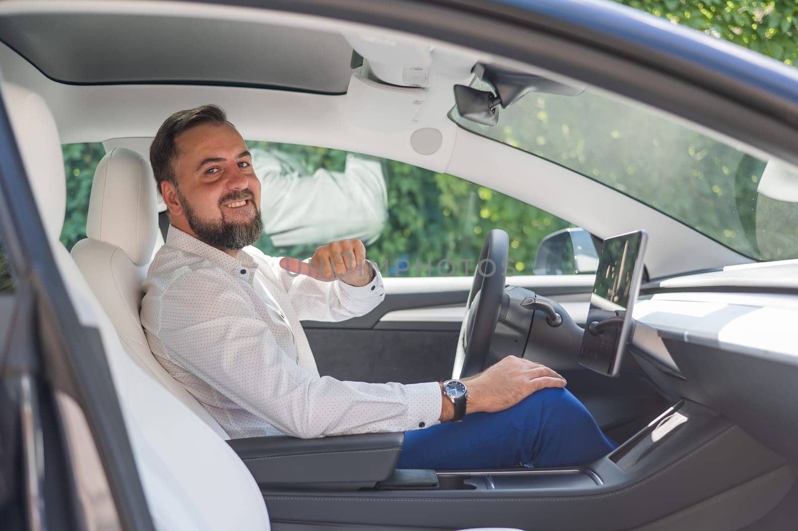 Caucasian bearded man in a suit driving a car