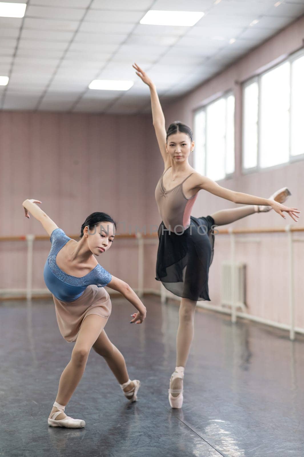 Two Asian ballerinas are dancing in the class