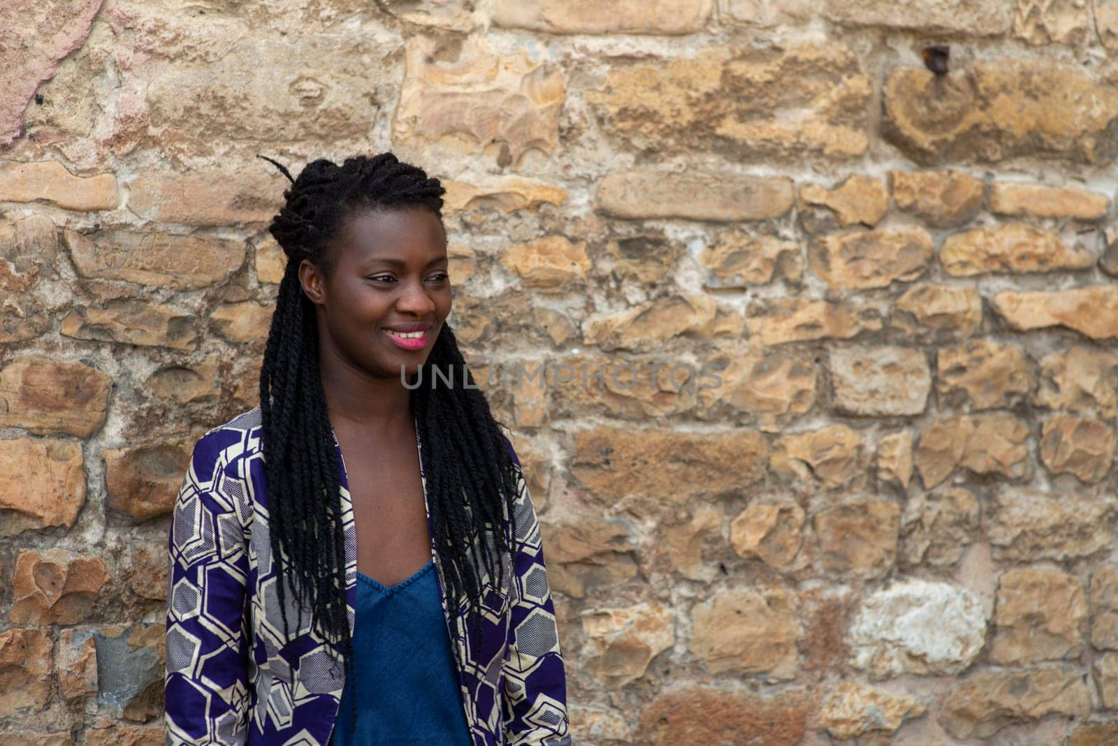 relaxed young black woman sitting. Stylish model. Braid dreadlock hairstyle. Confident African female in selective focus outdoors, fashion style, happiness concept. Outdoors.