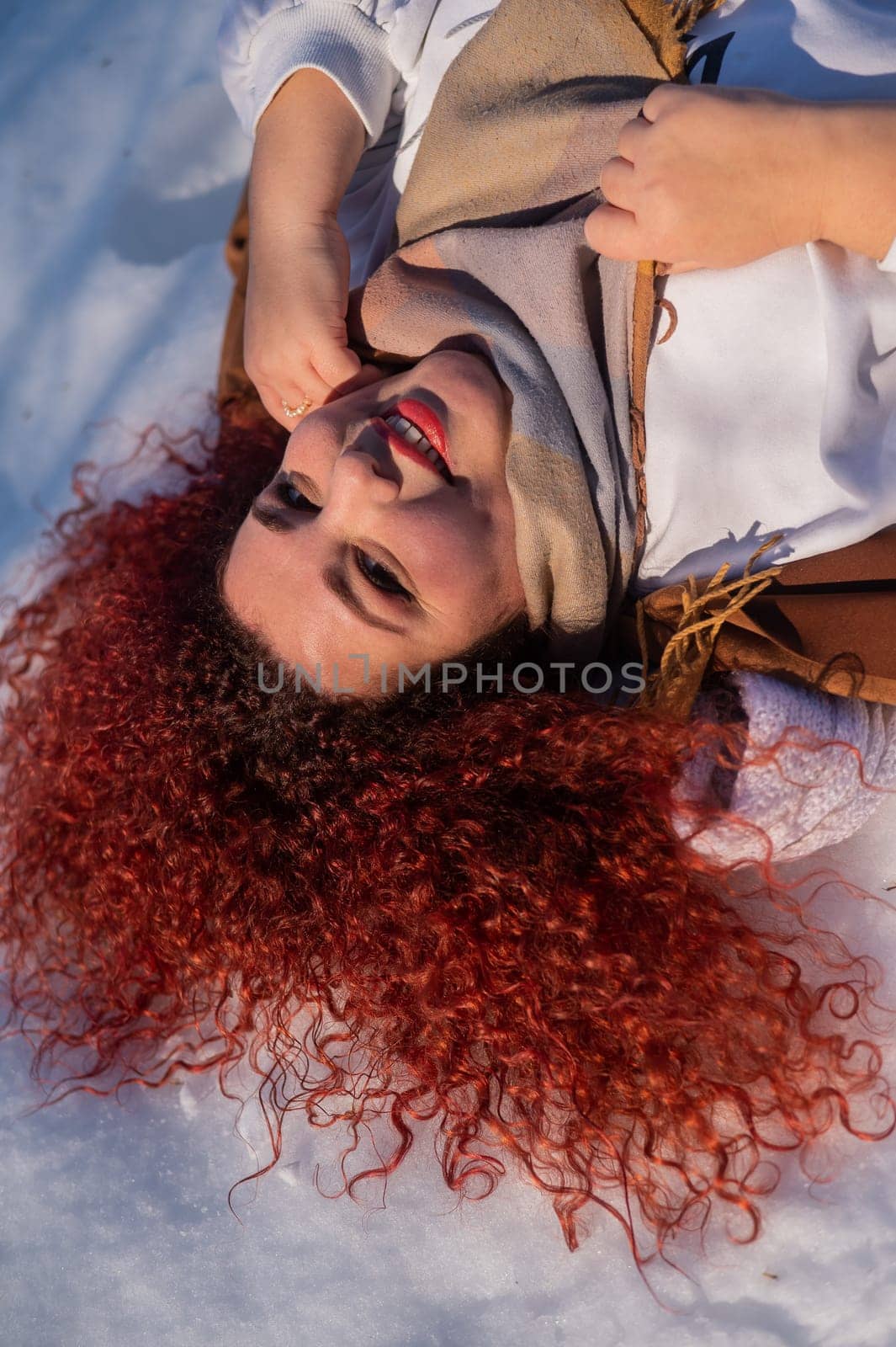 Top view of a fat red-haired woman lying on the snow. by mrwed54