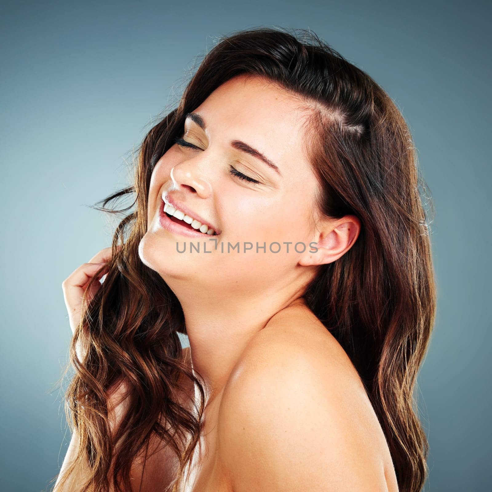 Beauty, skincare and hair care of woman in studio happy about cosmetics, makeup and keratin shampoo for shine and growth. Face of aesthetic model on blue background with glow from dermatology facial.