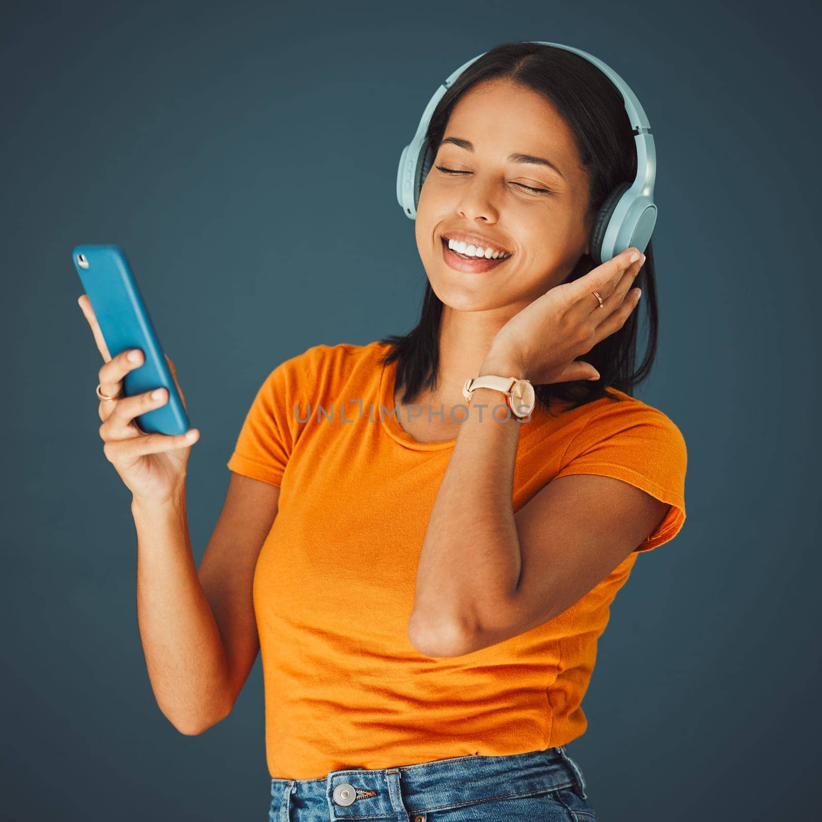 Radio, headphones and woman listening to music on phone or mobile app isolated against a studio background. Fun, sound and female enjoying and streaming a podcast or audio smiling and happy.