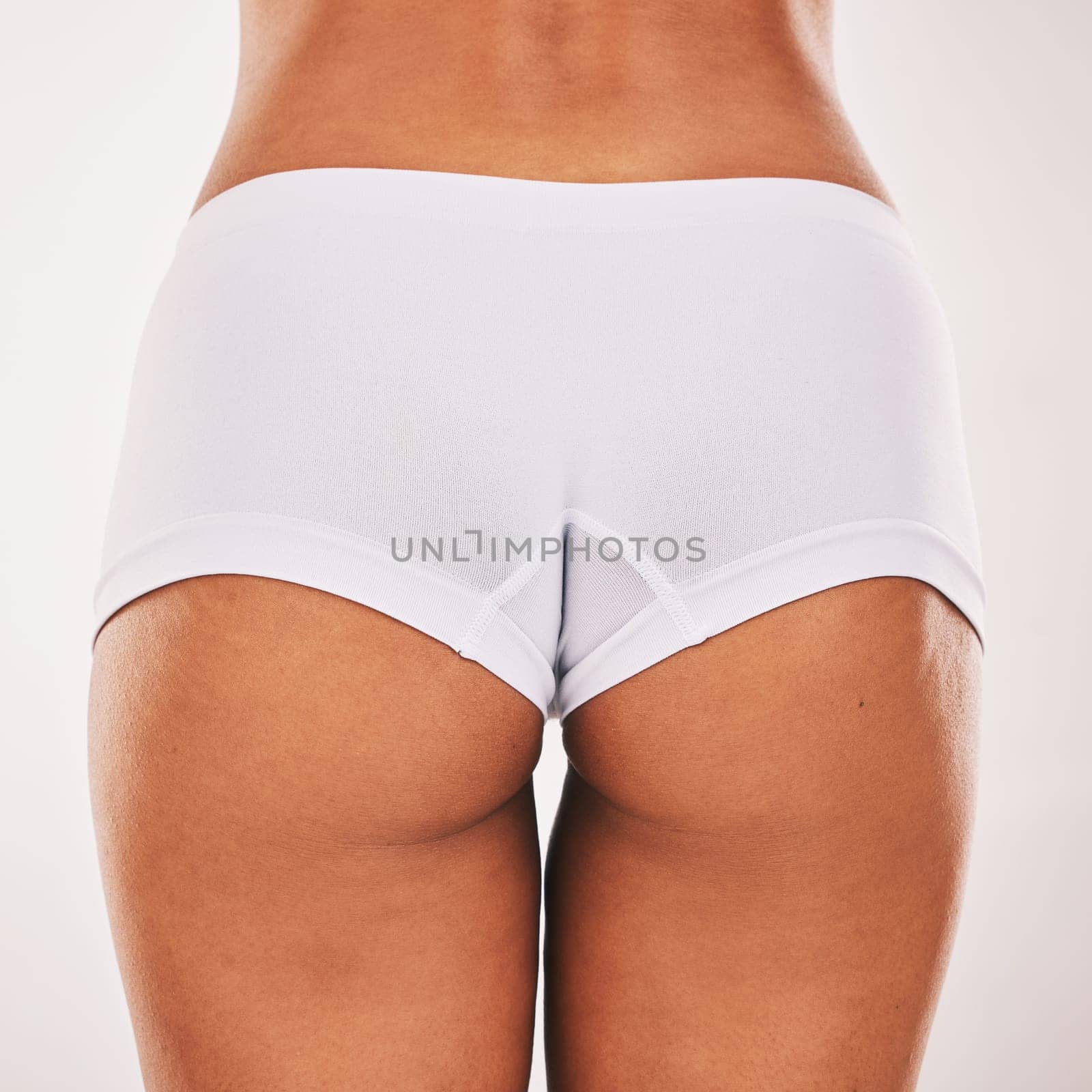 Buttocks, underwear and closeup with a model black woman in studio on a gray background from the back. Skin, real and bum in panties with a normal female posing to promote natural body positivity by YuriArcurs