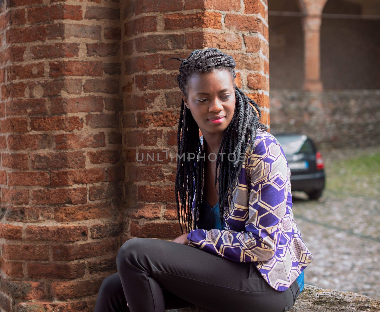 relaxed young black woman sitting. Stylish model. Braid dreadlock hairstyle. Confident African female in selective focus outdoors, fashion style, happiness concept. Outdoors.
