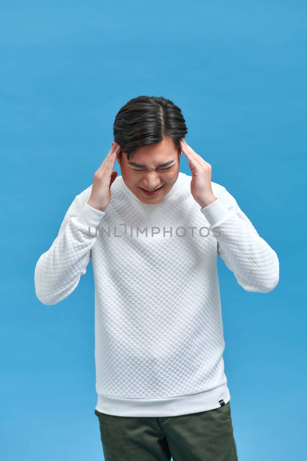 Young Asian man  touching head temples experiencing stress having troubles difficulties to resolve issues
