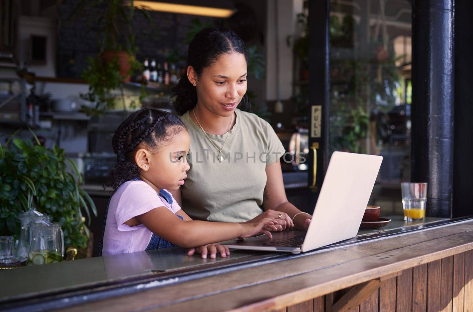 Black family, internet cafe or laptop with a mother and daughter together in the window of a restaurant. Kids, computer or education with a woman and female child sitting or bonding in a cafe by YuriArcurs