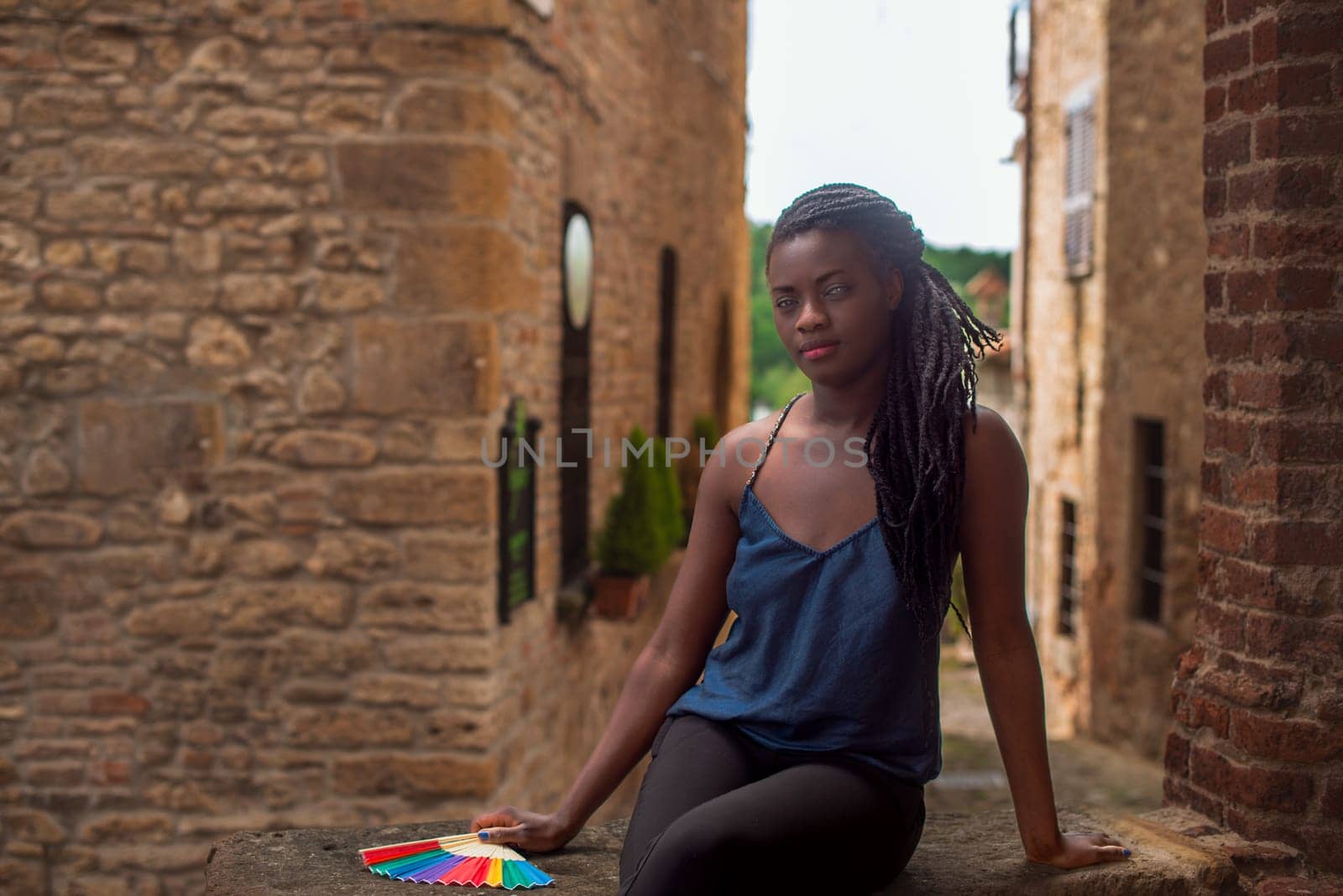 relaxed young black woman sitting. Stylish model. Braid dreadlock hairstyle. Confident African female in selective focus outdoors, fashion style, happiness concept. Outdoors.