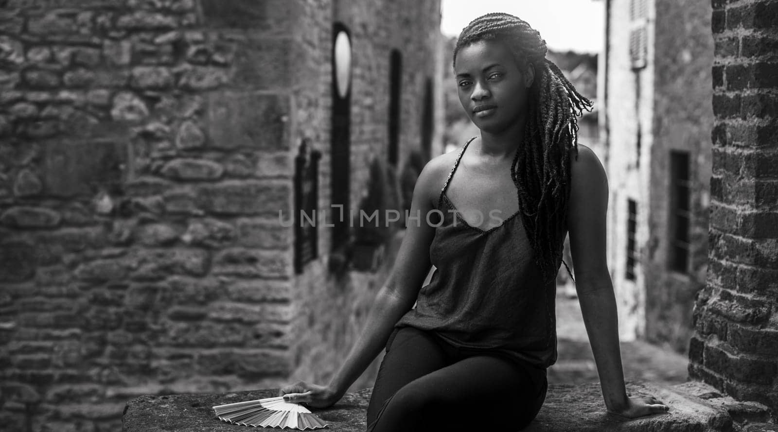 relaxed young black woman sitting. Stylish model. Braid dreadlock hairstyle. Confident African female in selective focus outdoors, fashion style, happiness concept. Outdoors.