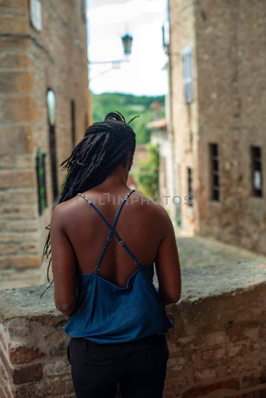 back of relaxed young black woman sitting. Stylish model. Braid dreadlock hairstyle. Confident African female in selective focus outdoors, fashion style, happiness concept. Outdoors.