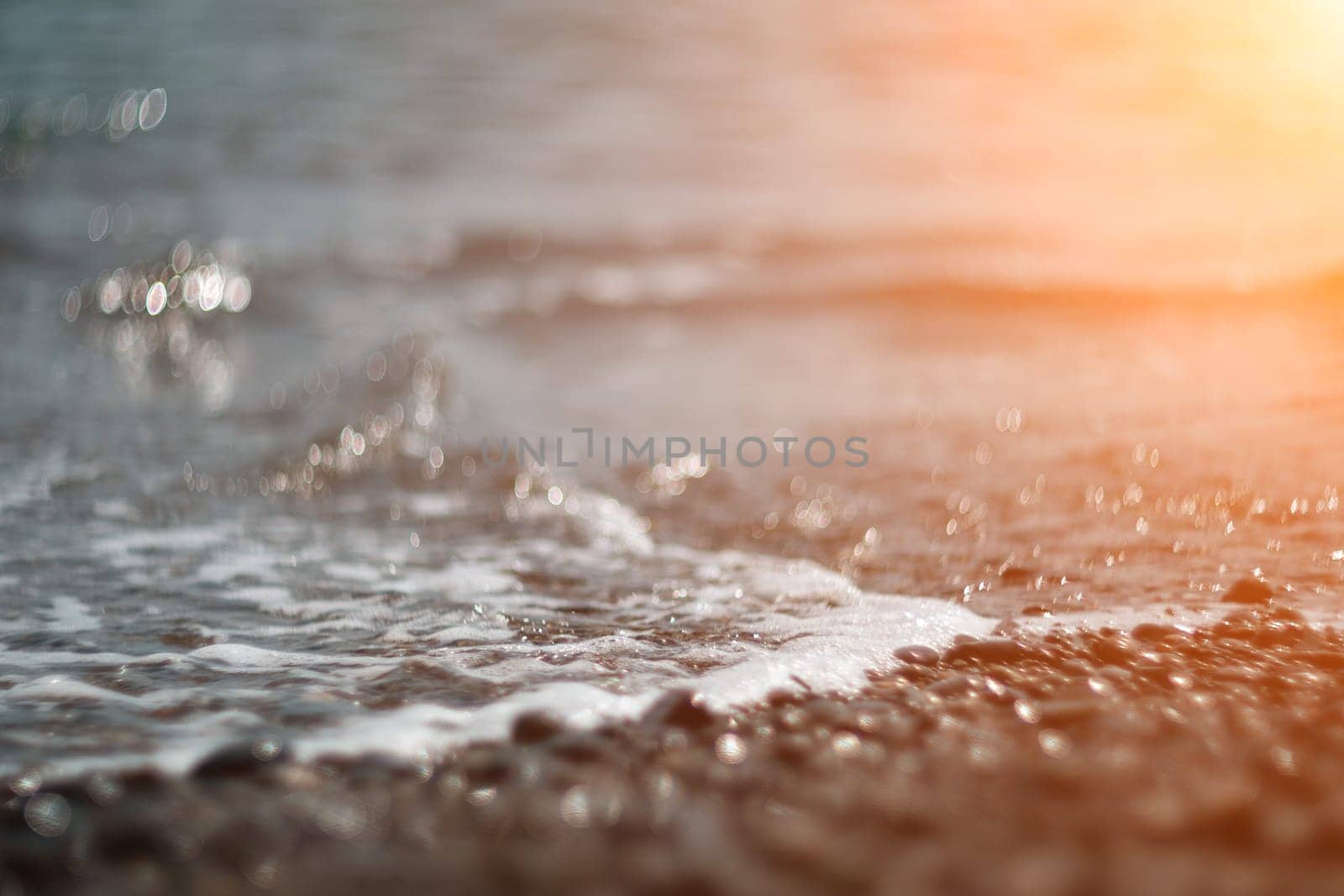 Abstract nature summer or spring ocean sea background. Small waves on water surface in motion blur with bokeh lights from sunrise.