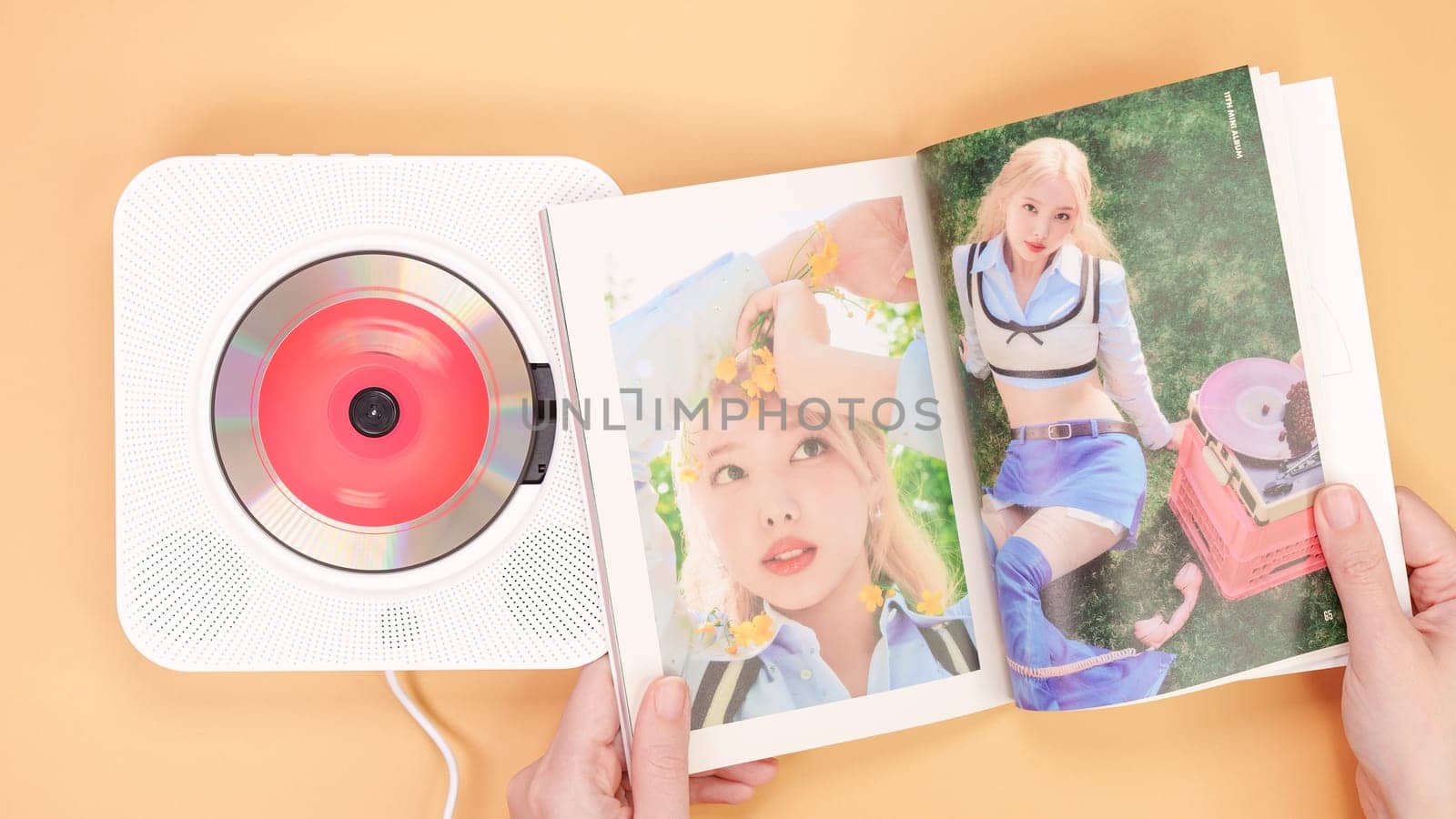 Hands holding Twice Between 1 and 2 mini Album photobook on yellow. Music CD player. South Korean girl group Twice. Space for text. Gatineau, QC Canada - December 27 2022