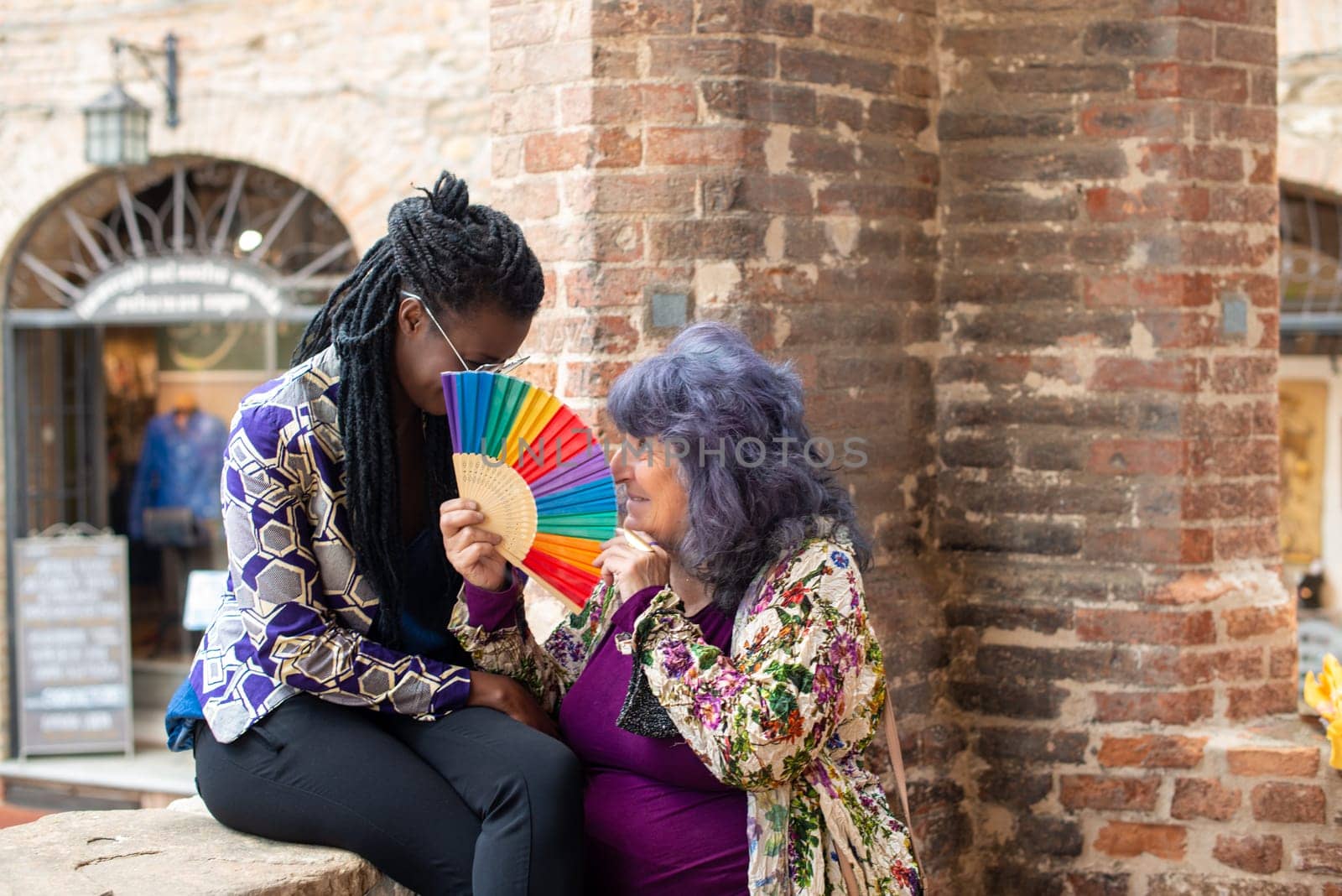 Diverse lesbian couple having fun in summertime in old village, outdoors. Funny expression. LGBT standout.