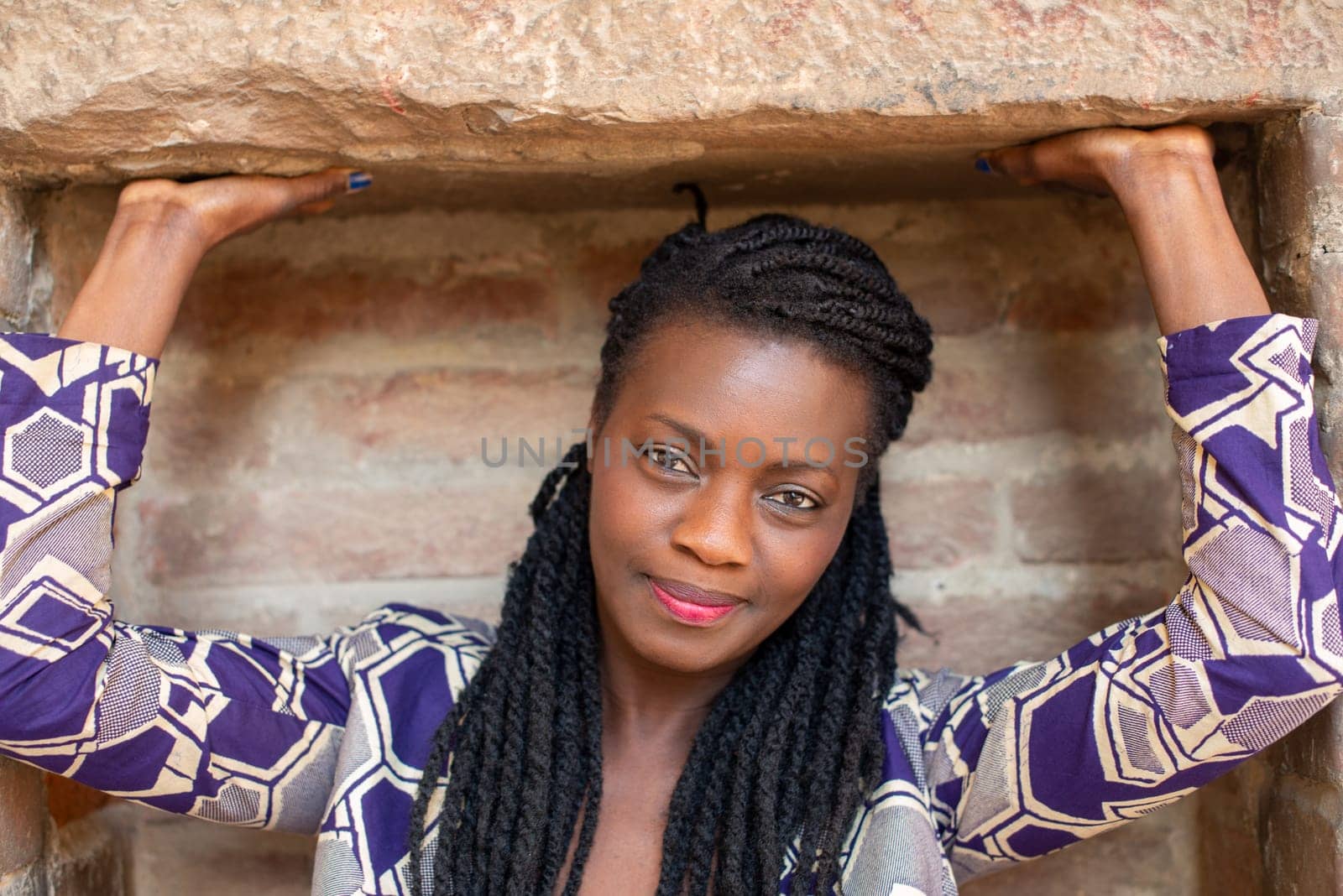 Happy young woman feeling confident in her style. Fashionable woman wearing dreadlocks braided hairstyle outdoors. Tourist traveling italian old village.