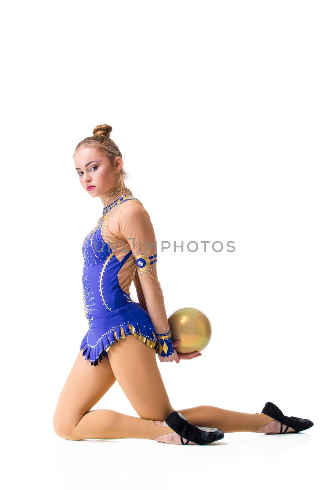 Young gymnast on a white background. Sporting exercises with a ball. Aerobics. Flexibility. Plastic study.