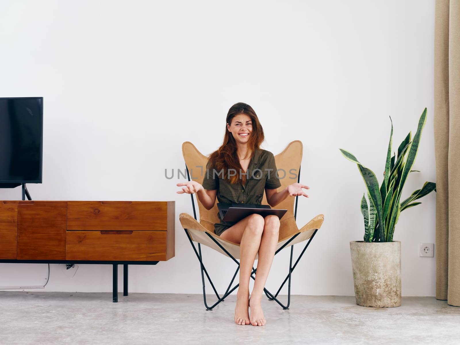 Woman student study sits on a chair with a laptop work at home smile, modern stylish interior Scandinavian lifestyle, copy space. High quality photo