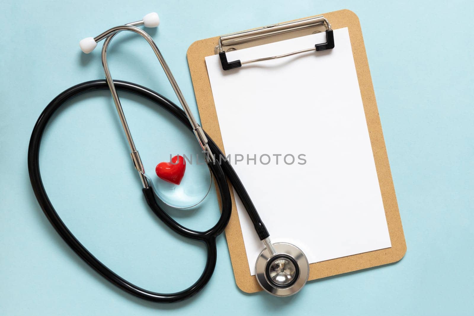 Cardiologist day. Stethoscope, flowers and heart shape, space for text on blue background.