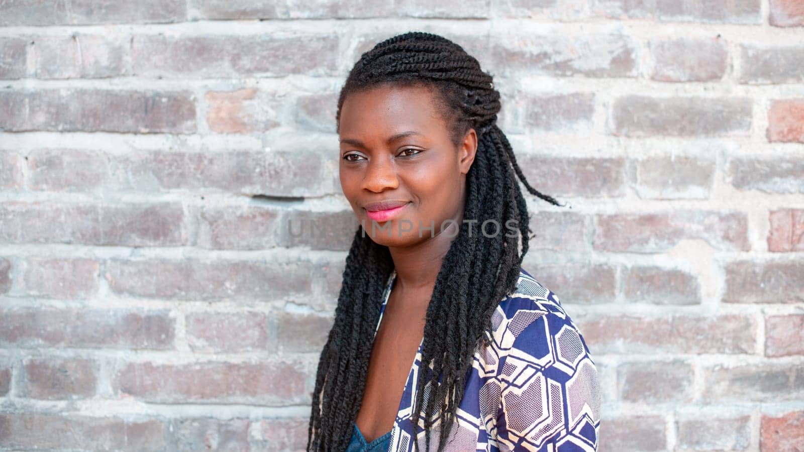 relaxed young black woman sitting. Stylish model. Braid dreadlock hairstyle. Confident African female in selective focus outdoors, fashion style, happiness concept. Outdoors.