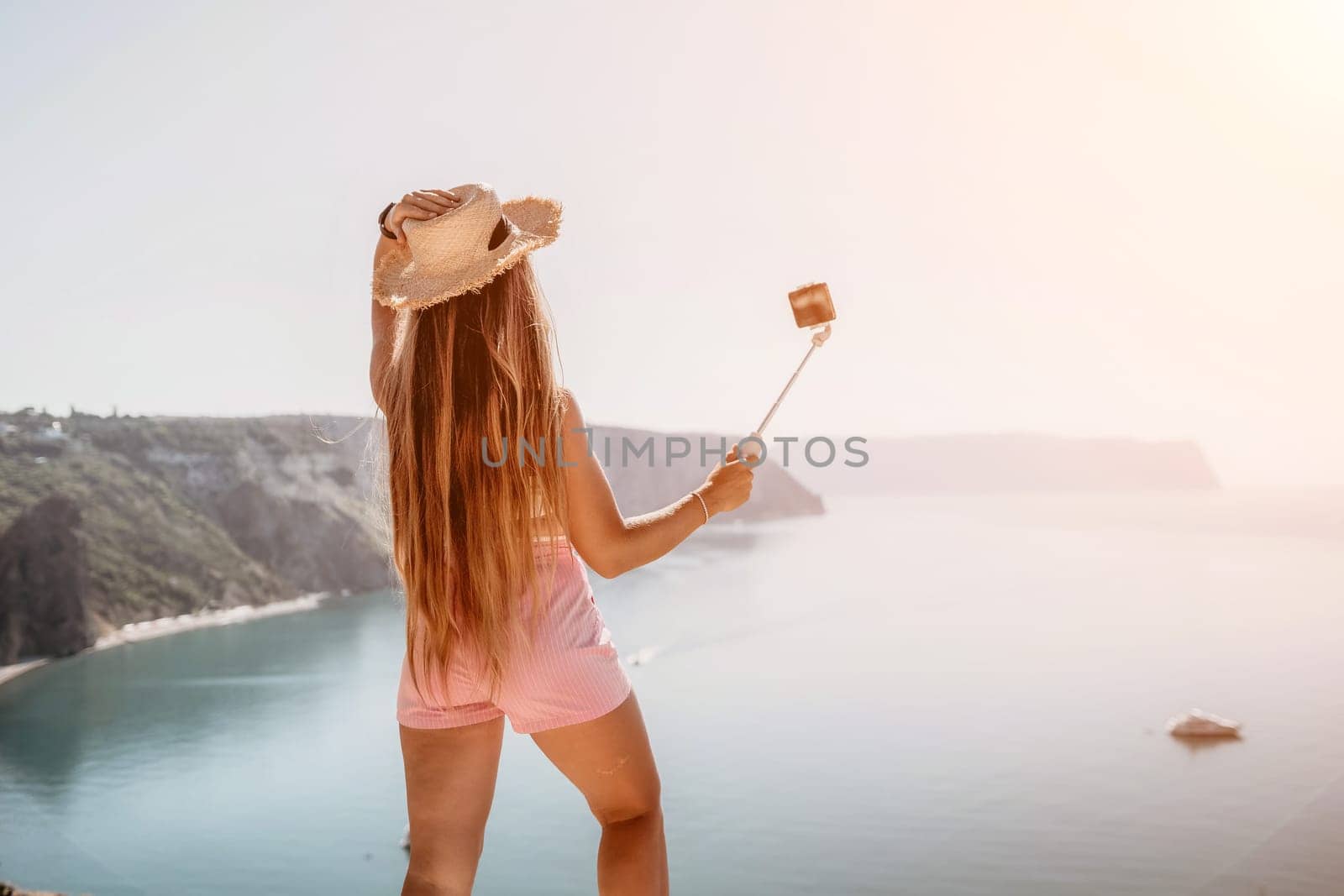 Digital nomad, Business woman working on laptop by the sea. Pretty lady typing on computer by the sea at sunset, makes a business transaction online from a distance. Freelance remote work on vacation