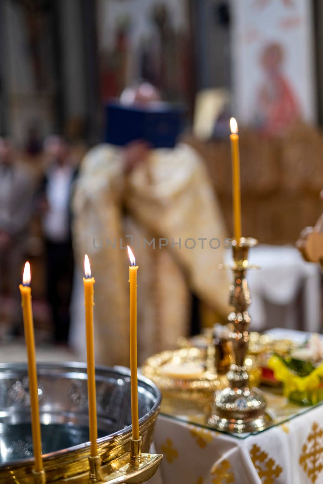 detail of candles with the orthodox parish priest celebrating mass