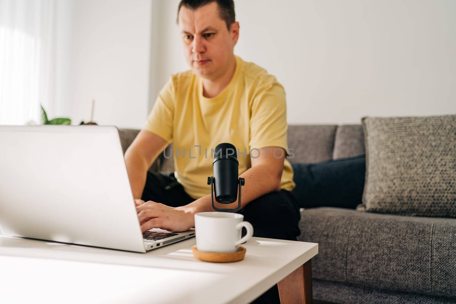 IT freelancer men with microphone typing in laptop working from home office. Programmers sitting on couch doing code review. Distance learning online education and work.