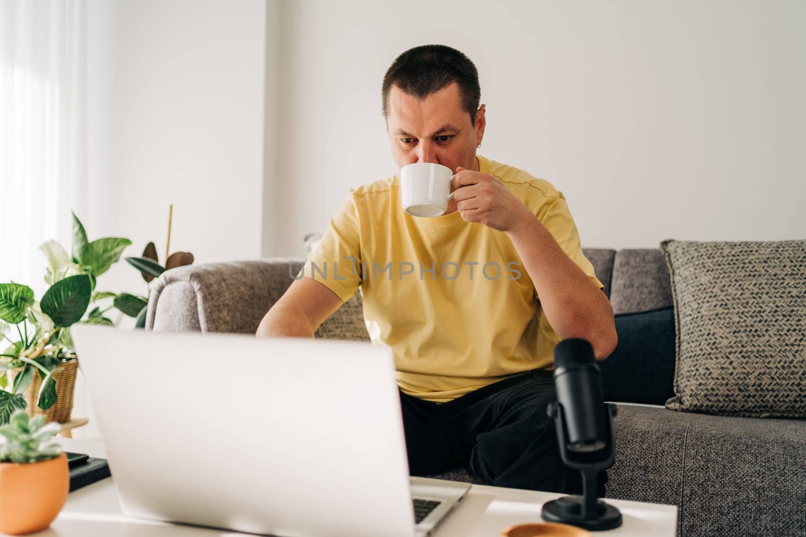 IT freelancer men with microphone typing in laptop working from home office. Programmers sitting on couch doing code review. Distance learning online education and work.