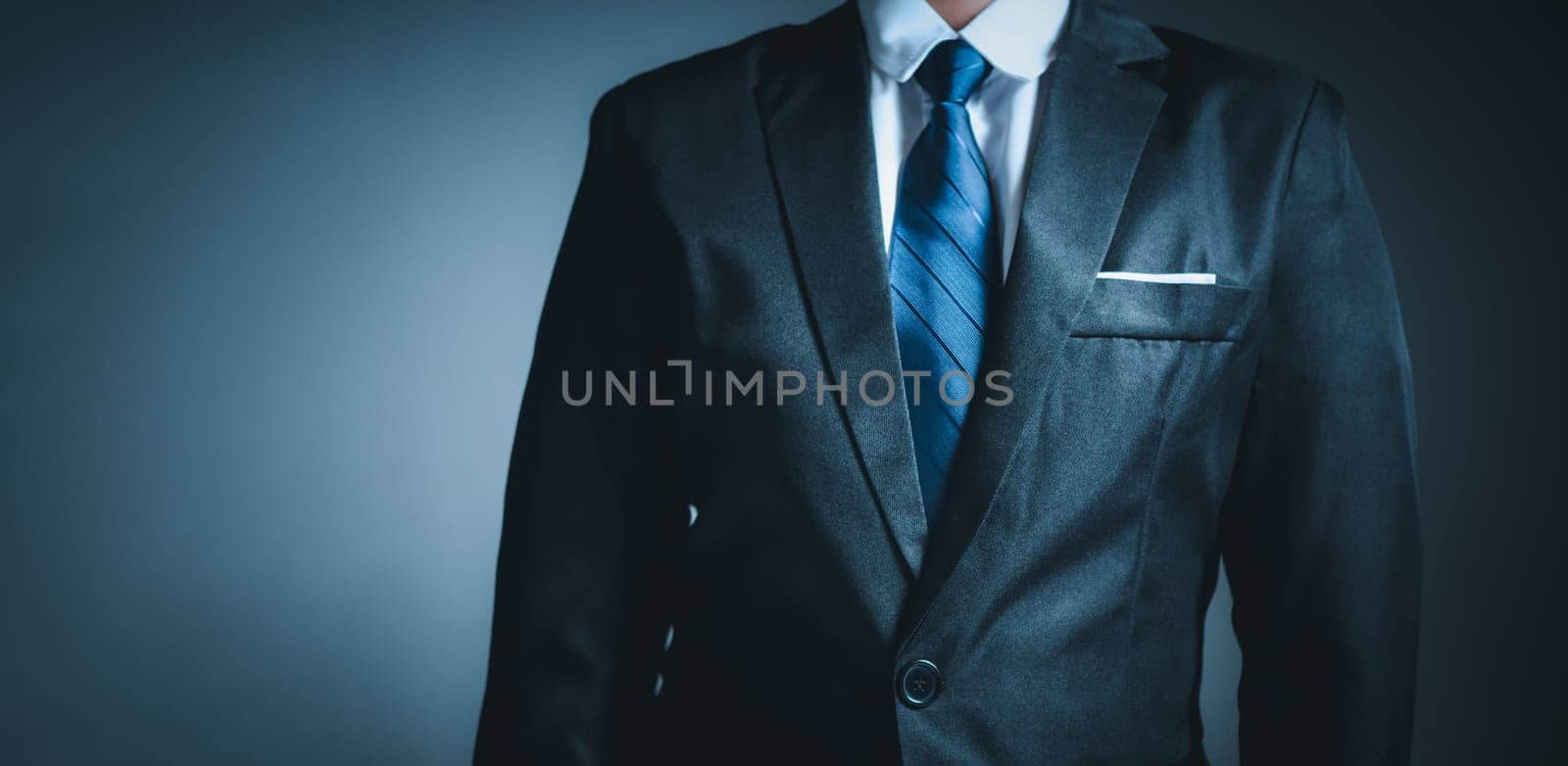 businessman standing on dark gradient background. business concept. suit. by Unimages2527
