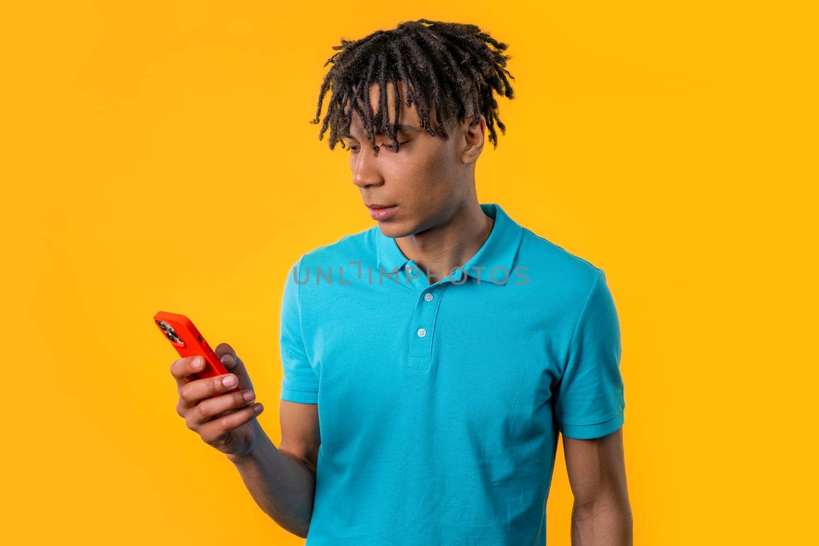 Handsome male teenager surfing internet on smartphone. Man with smile and joy on yellow background. Tech, success, happiness, social networks concept. High quality