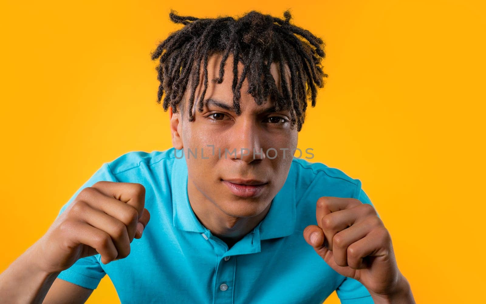 African man cannot believe eyes, squinting because cant see anything, yellow background. Poor eyesight, vision problems. Young guy with long dreadlocks hairstyle.
