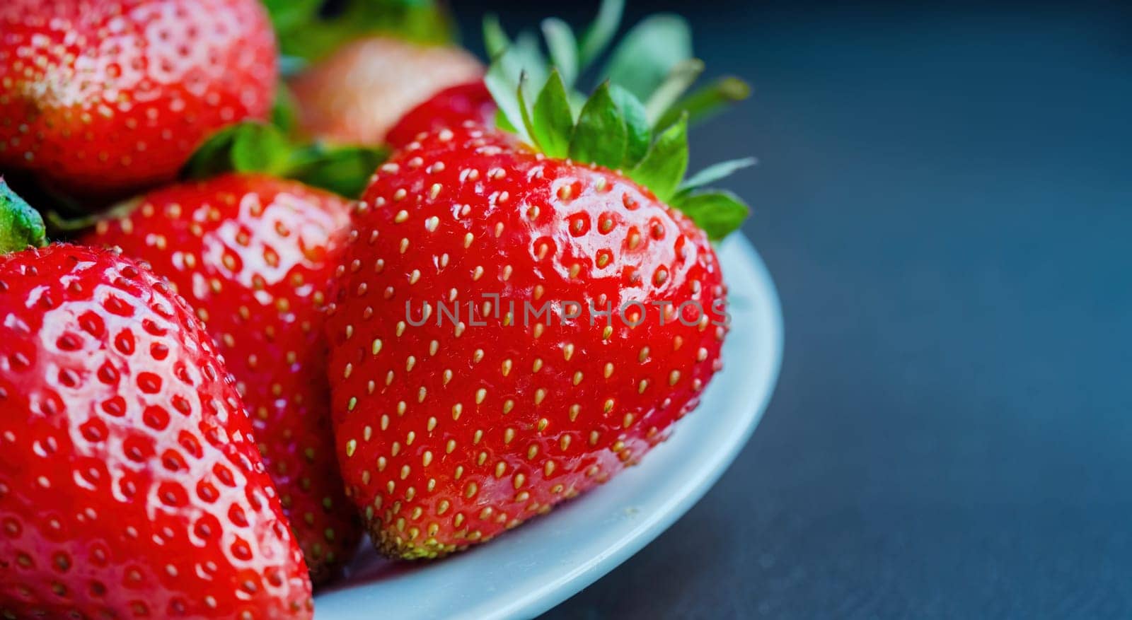 Red Organic Strawberries in a Bowl Ready to Eat. Strawberries laying in heap in white porcelain bowl. Copy space for text or banner. by Renisons