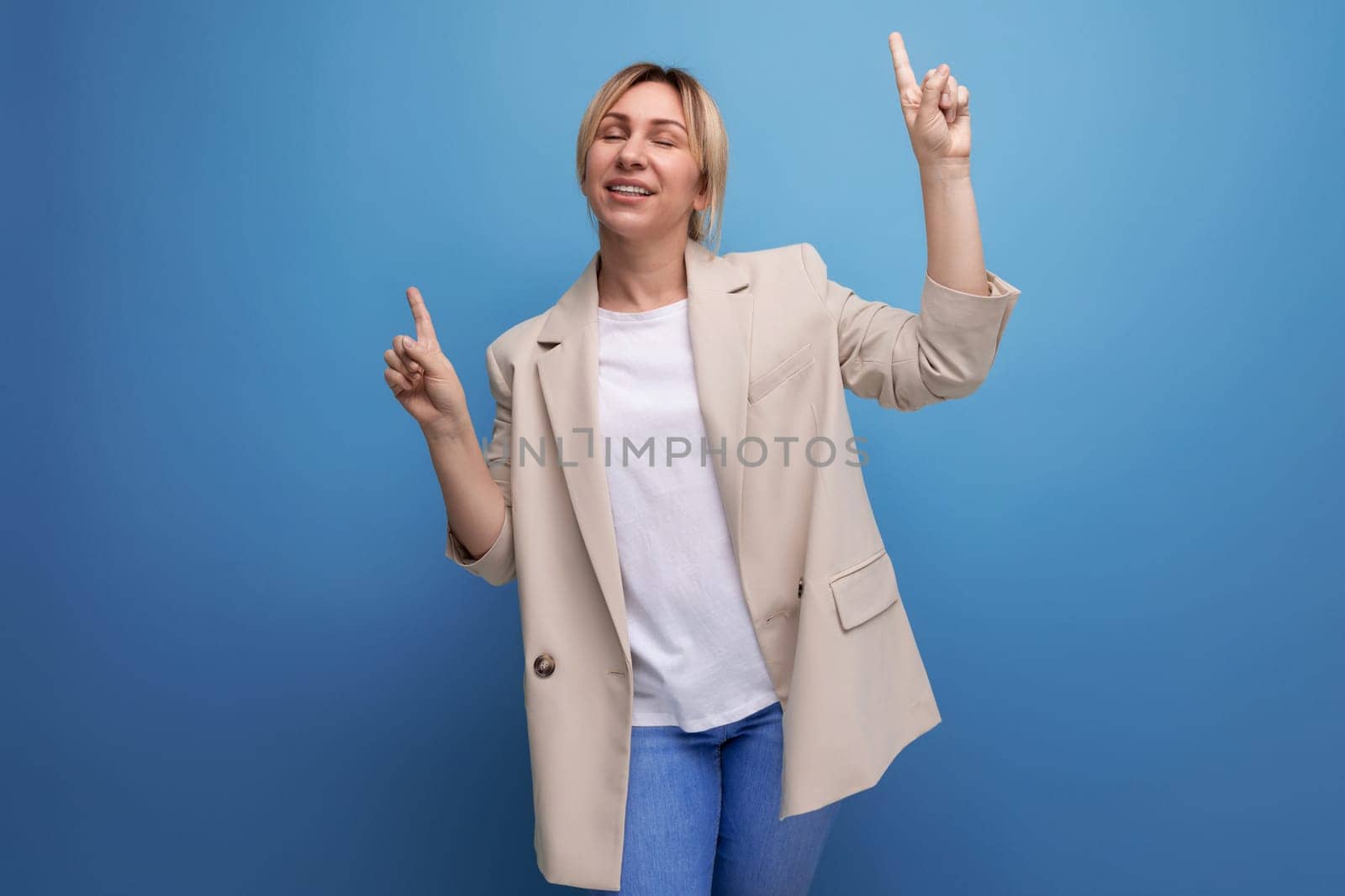 cheerful blonde young woman in jacket on studio background with copy space.