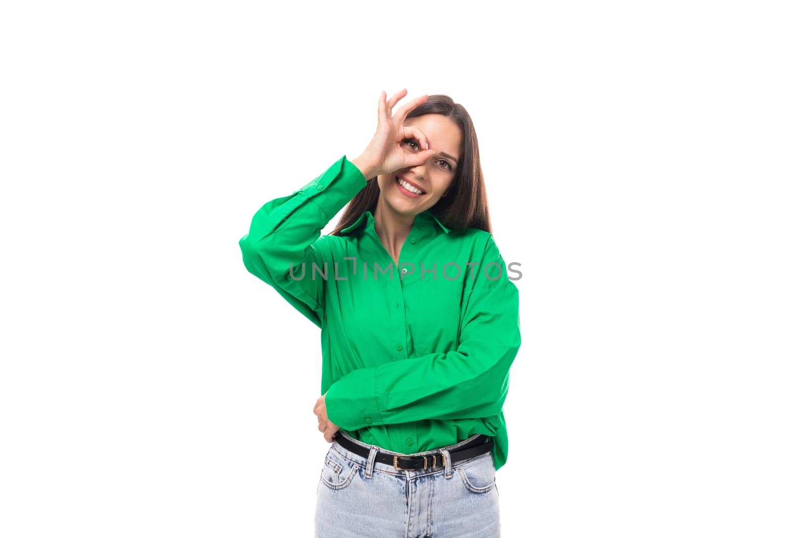 smiling kind well-groomed slim european young brunette woman with makeup in a green shirt on a white background with copy space for banner.