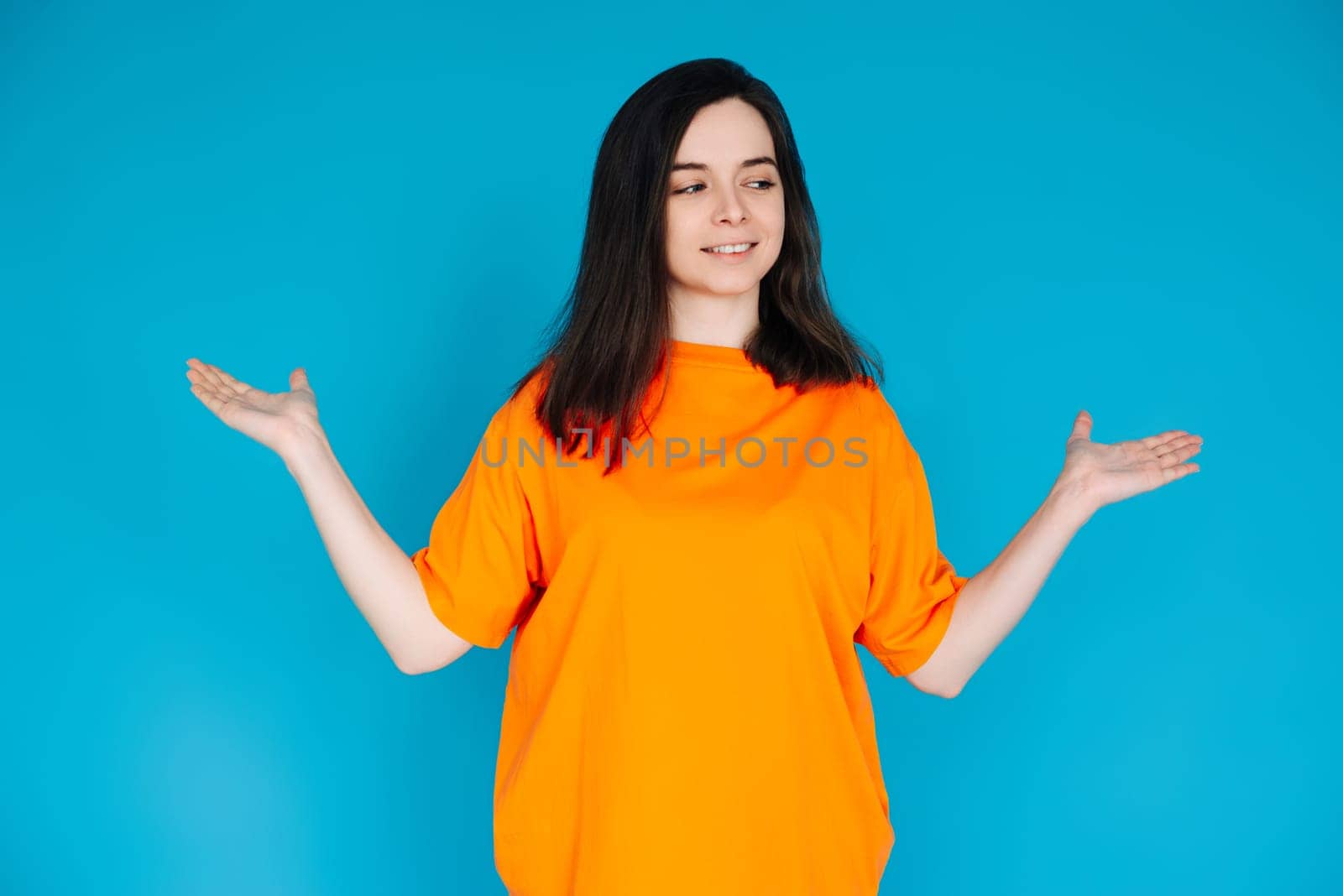 Smiling Young Woman Holding Empty Copy Space in Palms, Attractive Female Model, Isolated on Bright Blue Background, Portrait Photo.