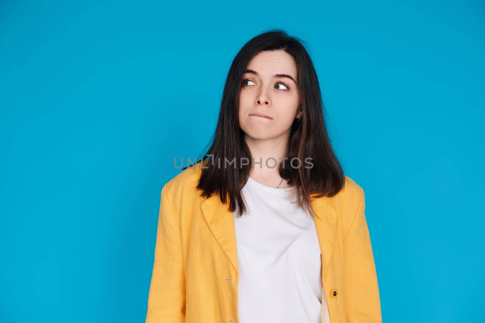 Serene Young Woman Contemplating, Gazing into Empty Space, Thoughtful Young Woman in Captivating Portrait, Lost in Contemplation, Isolated on Blue Background.