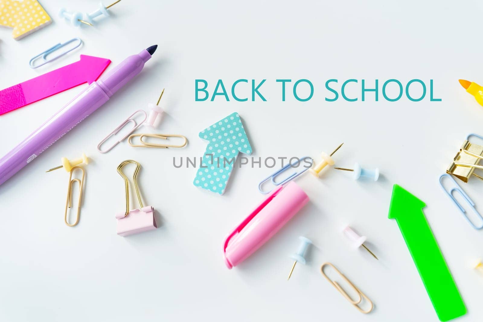 Top view of bright colored school supplies with blank paper and back to school lettering
