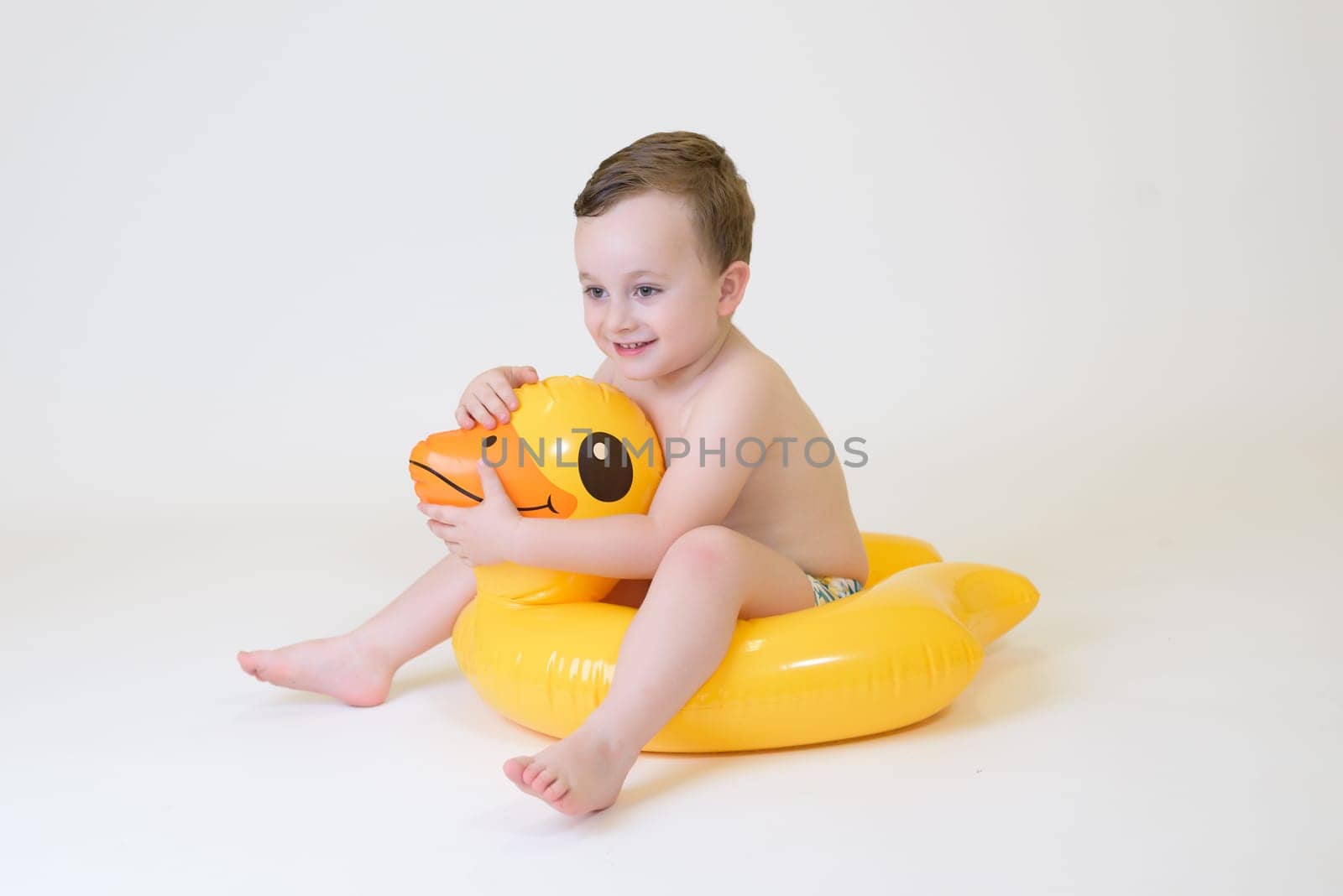 adorable boy sitting on a duck float on a white background. Summer Vacation.