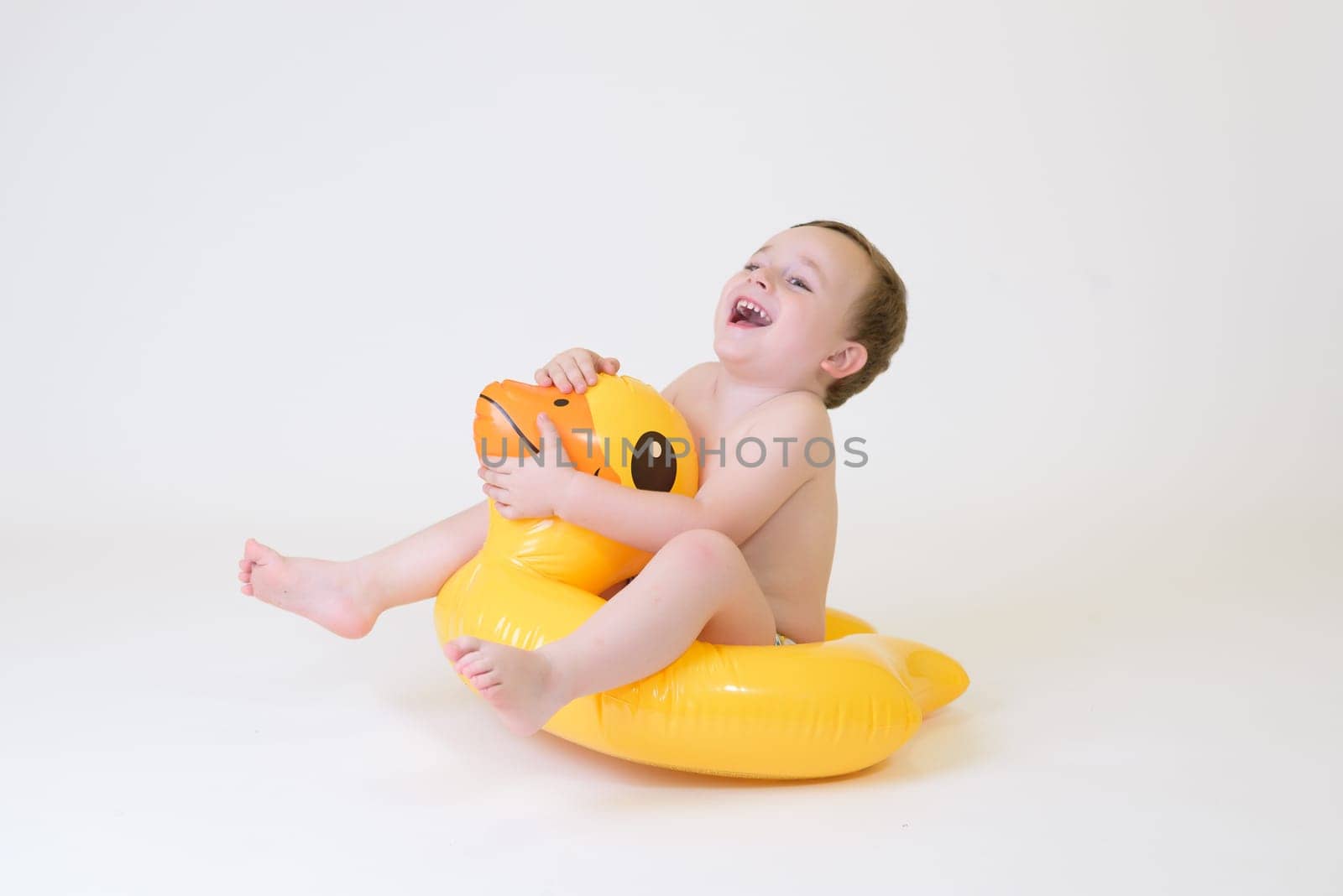 adorable boy sitting on a duck float on a white background. Summer Vacation by jcdiazhidalgo
