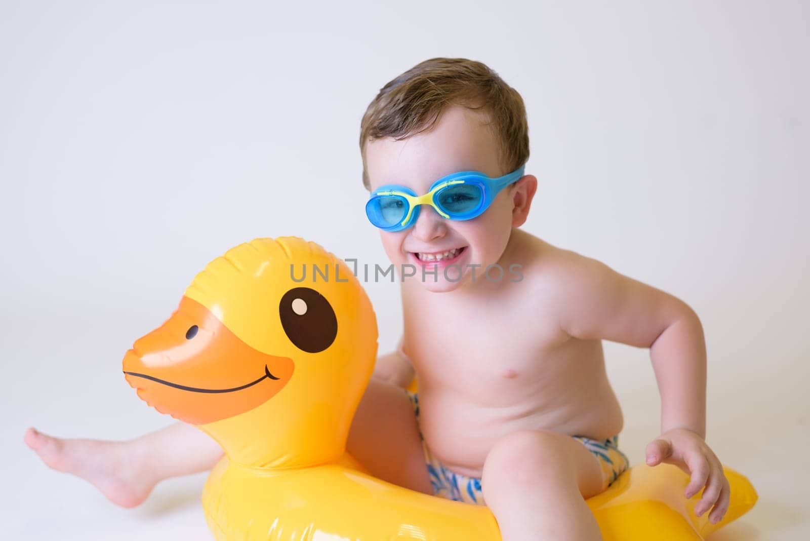 cute boy with inflatable float and diving goggles on white background.