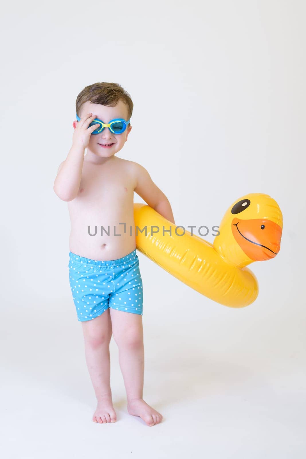 cute boy with inflatable float and diving goggles on white background.