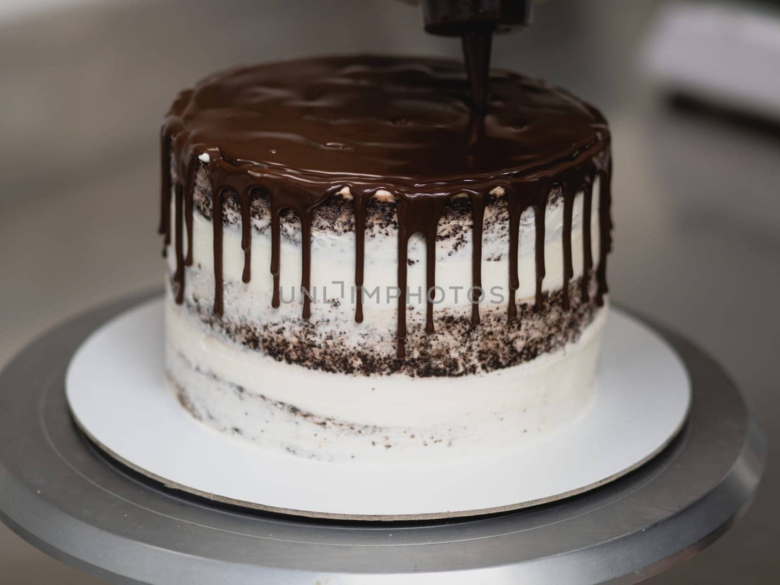 pastry chef preparing a chocolate frosted dripped icing cup cake with sweet fruit topping and golden brush strokes