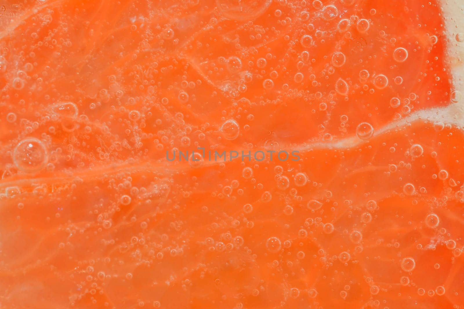 Slice of ripe grapefruit in water. Close-up of grapefruit in liquid with bubbles. Slice of ripe grapefruit in sparkling water. Macro horizontal image of fruit in carbonated water