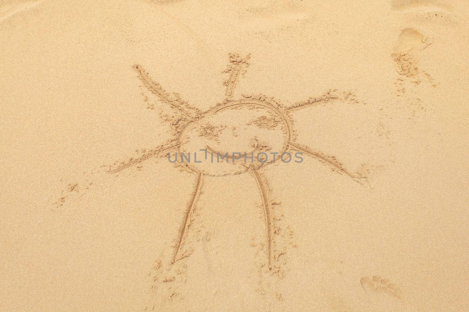 Kid drawn sun in wet sand on the beach.