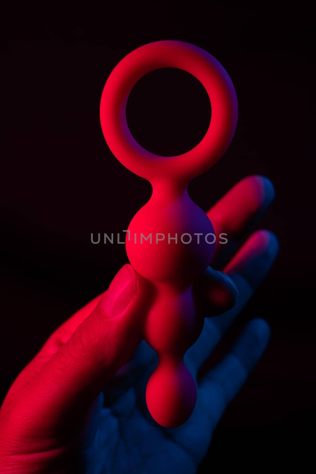 Woman holding anal beads in neon pink blue light