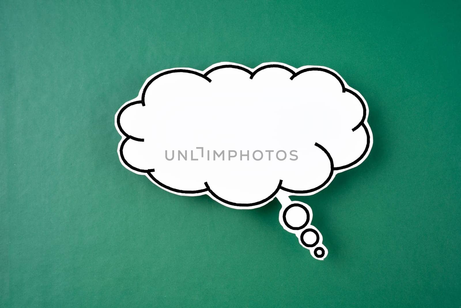 The White speech bubble shaped post it note on green background with copy space. by Gamjai