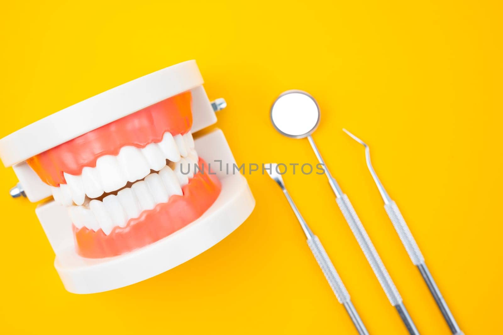 The Dentures model and instrument dental on yellow background. by Gamjai