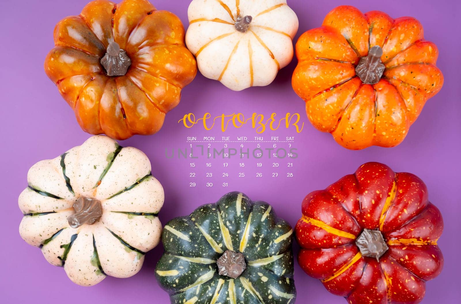 October 2023 Calendar and pumpkins on purple cardboard background.