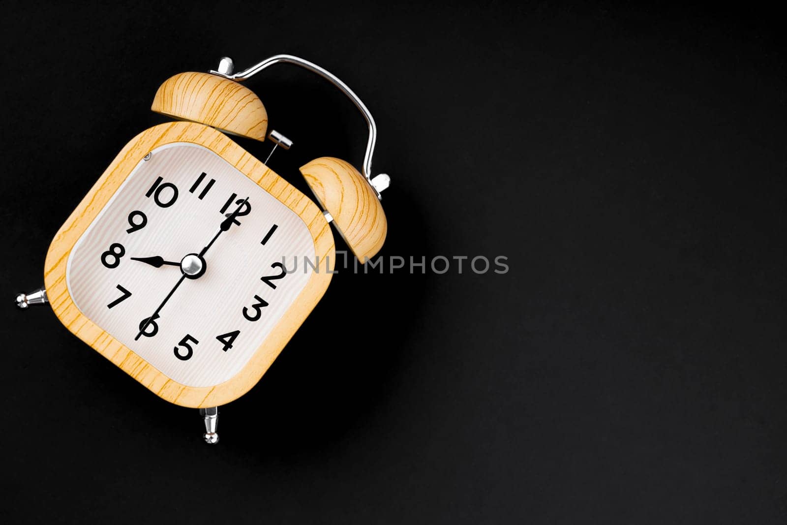 A Vintage wooden alarm clock on black background with copy space. by Gamjai