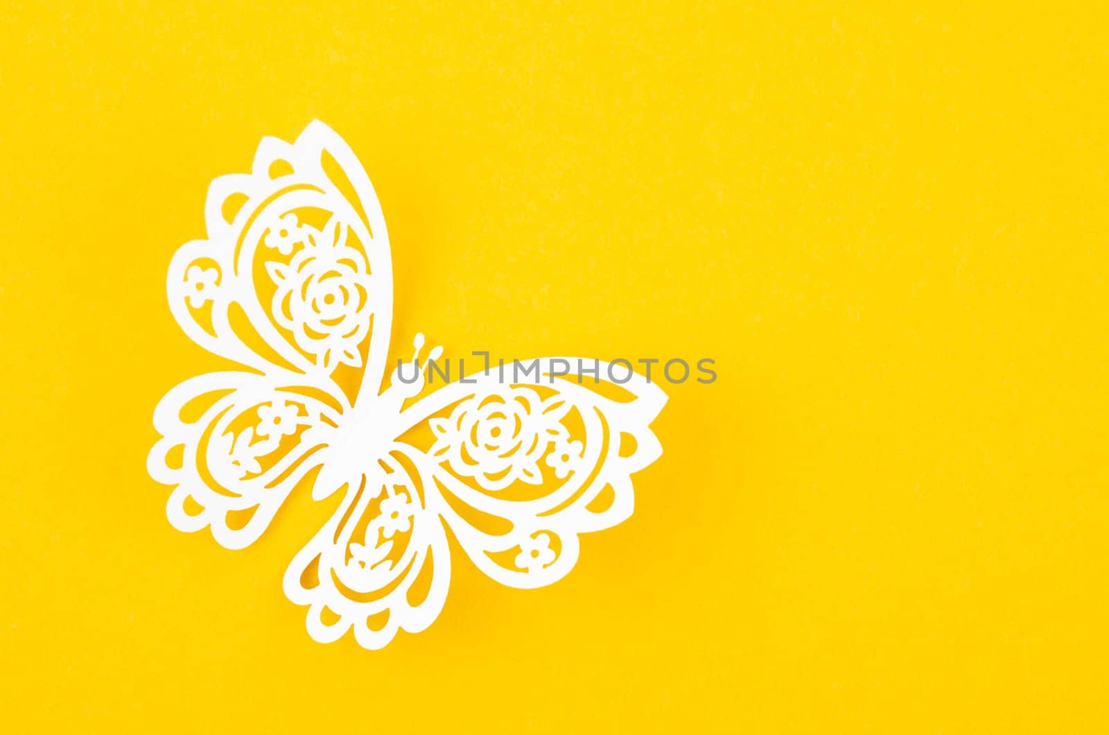 Paper butterfly carve on a yellow background with empty space.