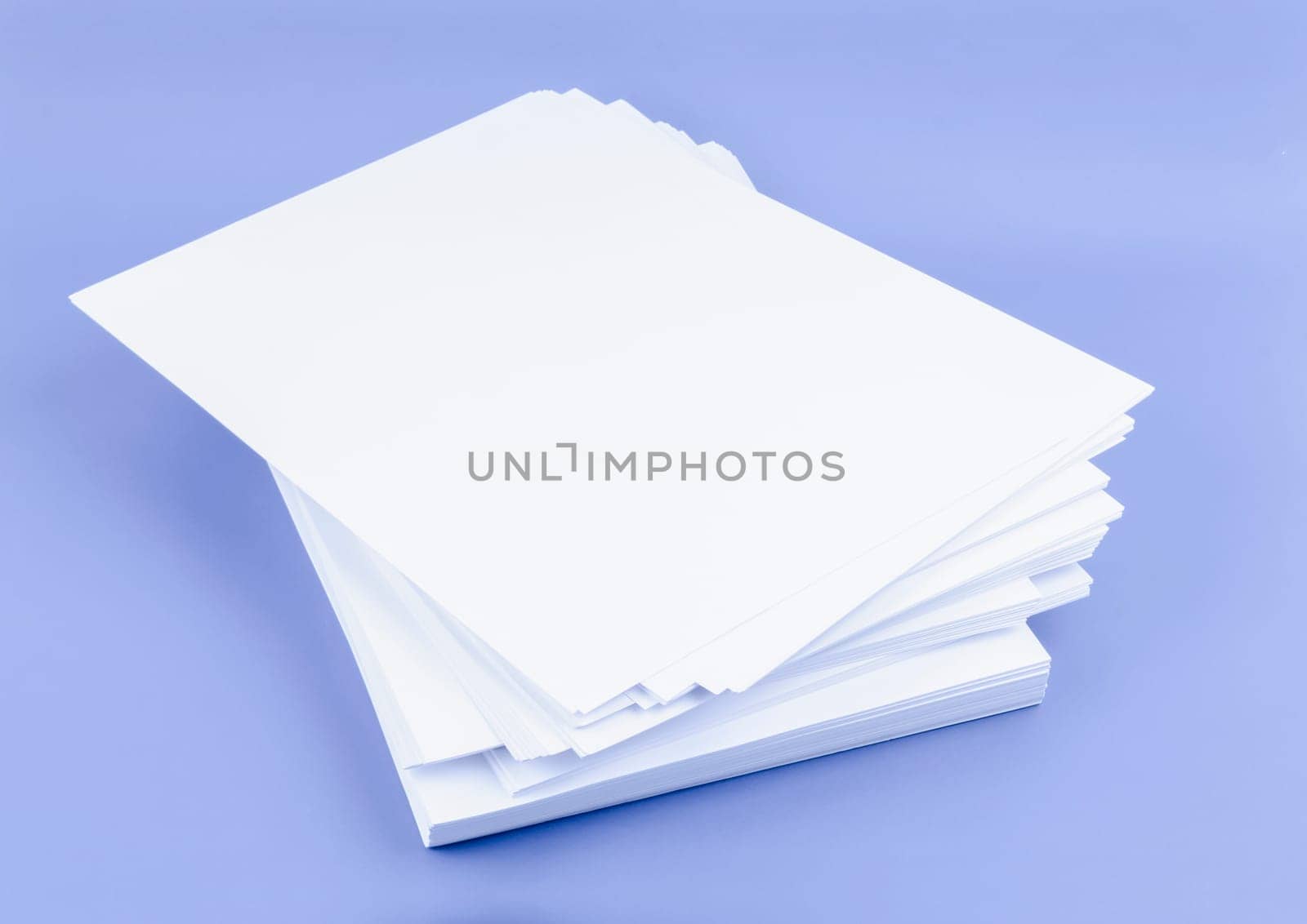 Stack of blank A4 paper sheets on blue background.