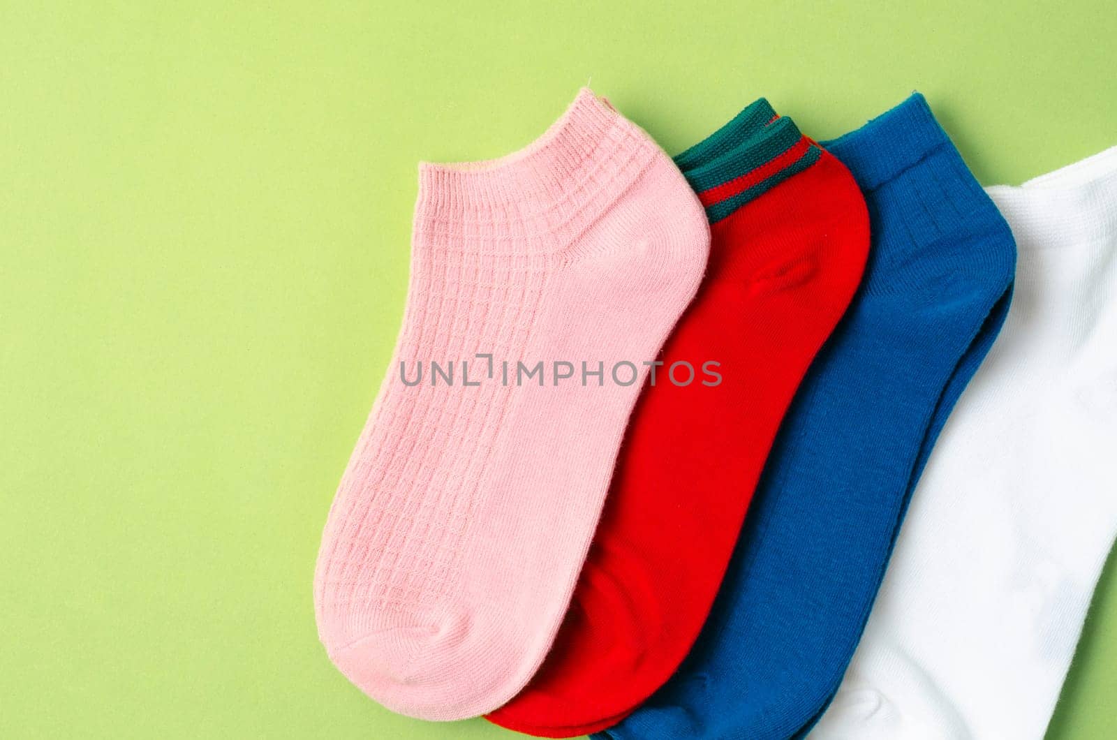 Socks of different colors on green background.